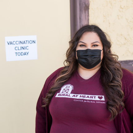 Woman wearing mask, standing in front of "Vaccination Clinic Today" sign