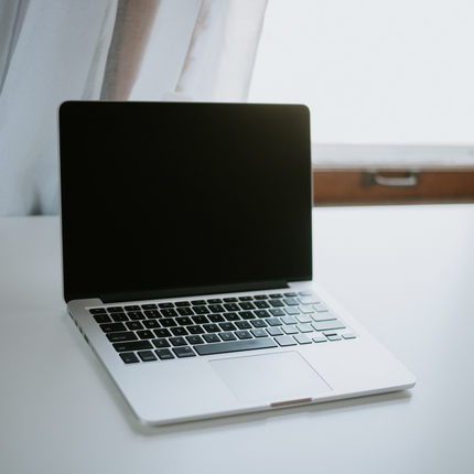 laptop computer sitting on a white table with a window in the background
