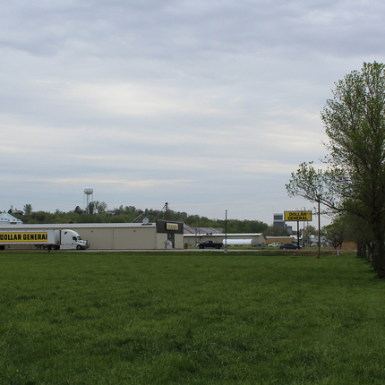 Dollar General building with Dollar General Truck in front at edge of town