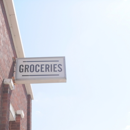 White sign saying groceries written in black on the side of a building.
