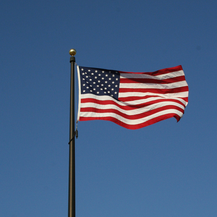 Bandera estadounidense vuela con el viento en un cielo azul oscuro sin nuves