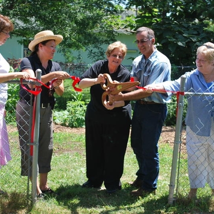 Folks cutting a ribbon to open a community garden