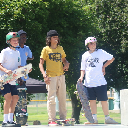 group of boys standing, holding skateboards, looking to distance
