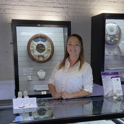 Woman standing behind jewelry counter, posing