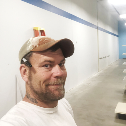 Man in construction clothes with new wall behind him