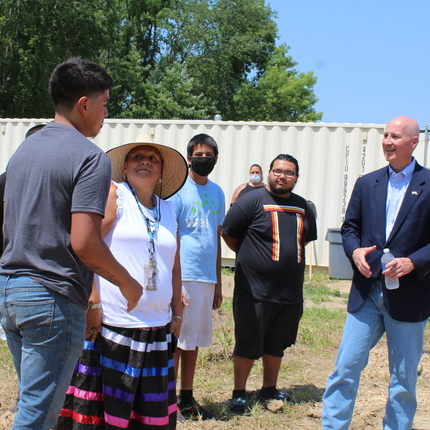 High school students and female teacher in garden hat greeting Nebraska governor in a garden