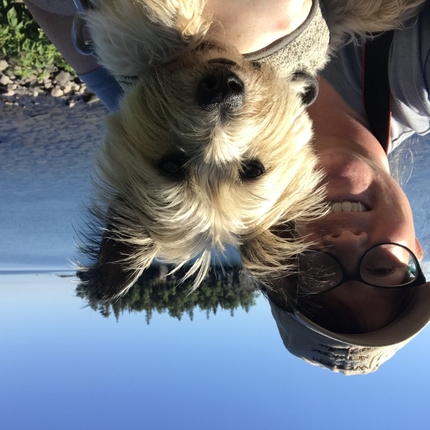 Mujer y un perro con un lago y una isla al fondo