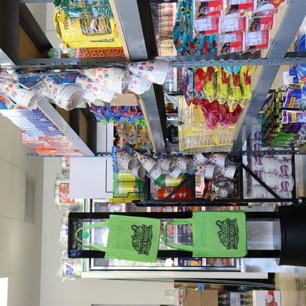 Racks of goods in a grocery store with hanging tote bags