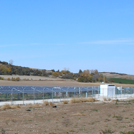 Solar arrays at a public power owned solar farm, with building containing large battery