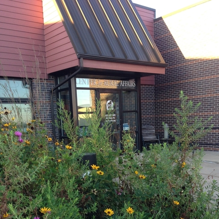 Brick building with grass and plants out front.
