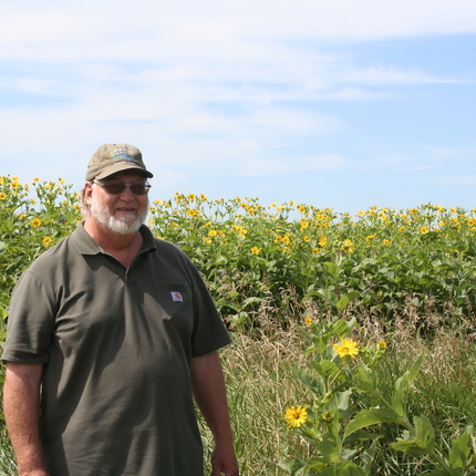 Mark Tjelmeland standing in front of sunflowers