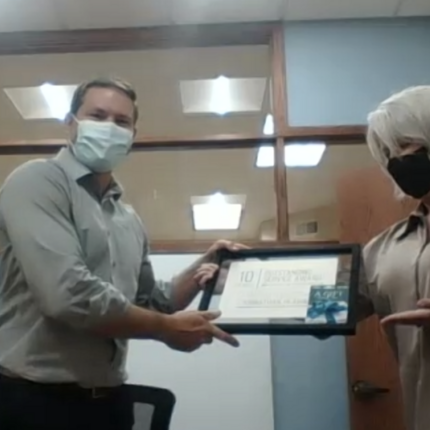Hombre (Johnathan Hladik) recibiendo premio de una mujer.