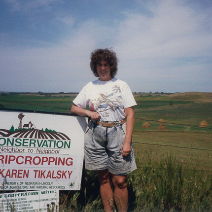 Woman standing beside Conservation sign in field