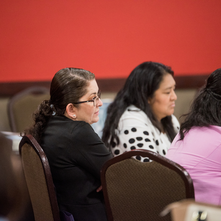Three women sitting at a table, listening