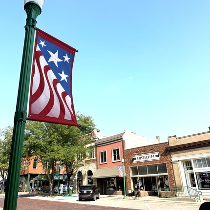 American flag design banner on light pole with buildings in the background