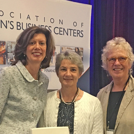 Three women standing on stage at conference