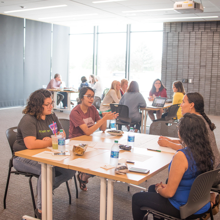 Mujeres conversando, sentadas alrededor de una mesa.