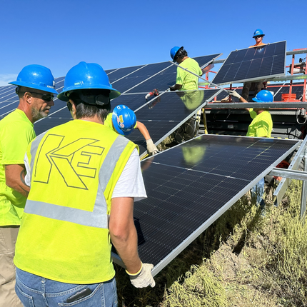 People is yellow safety vests move solar panels into place. 