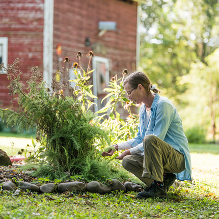 Woman business owner with herbs in front of barn