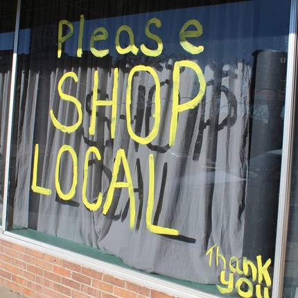 Fachada con el letrero pintado "Por favor, compre en comercios locales".