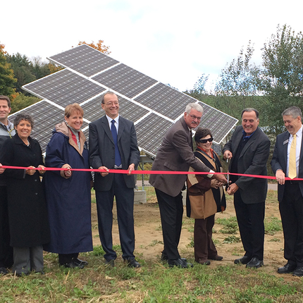 Group of people at a ribbon cutting in front of solar array