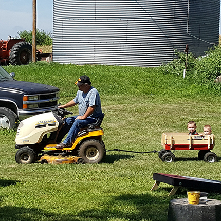 Man on lawnmower pulling children in wagon