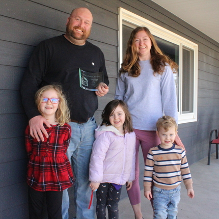 A family standing on the porch of their home.