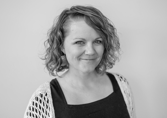 White female with shoulder-length curly hair. Black and white headshot.
