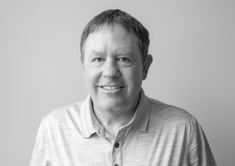 Photo of a man with brownish short hair, wearing a light colored polo shirt, smiling at the camera