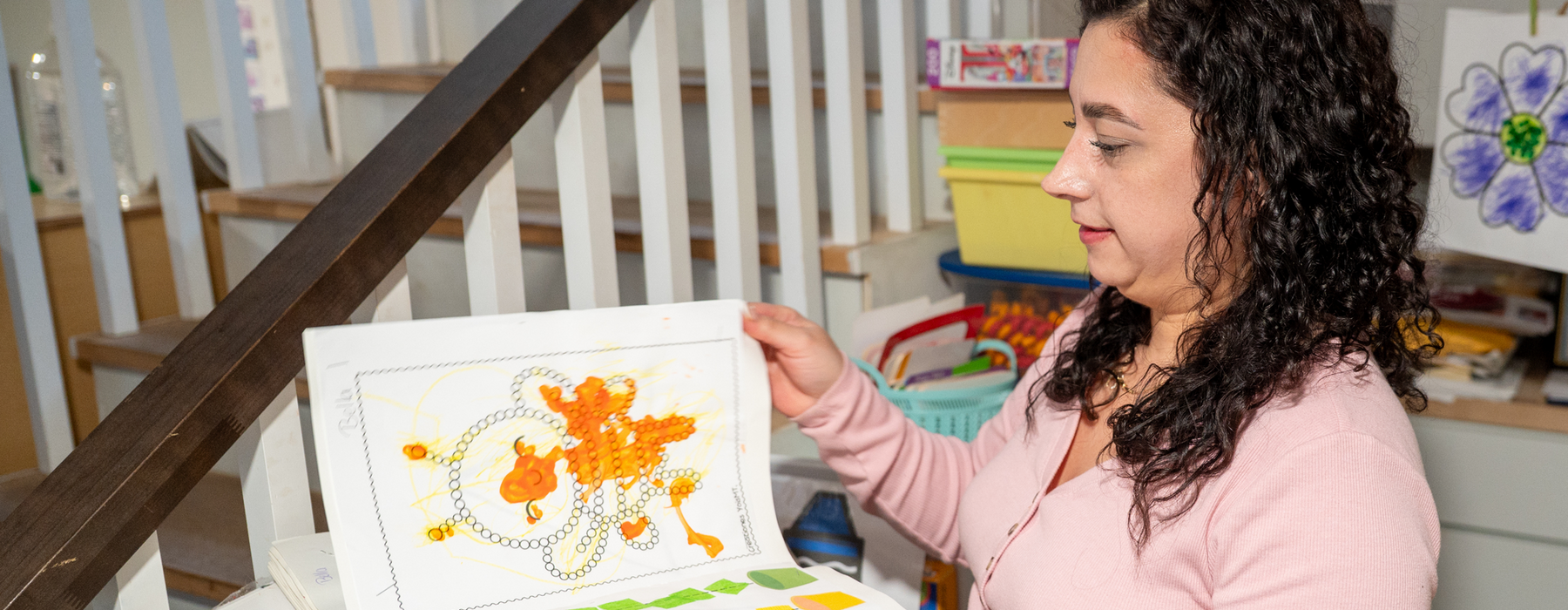 Woman stands holding a children's art book.