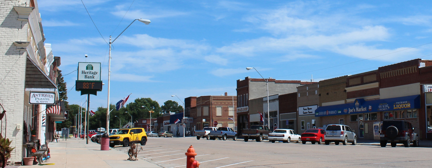 Calle principal de una pequeña ciudad con automóviles a lo largo de la calle y negocios a lo largo de la calle. Cielo azul.