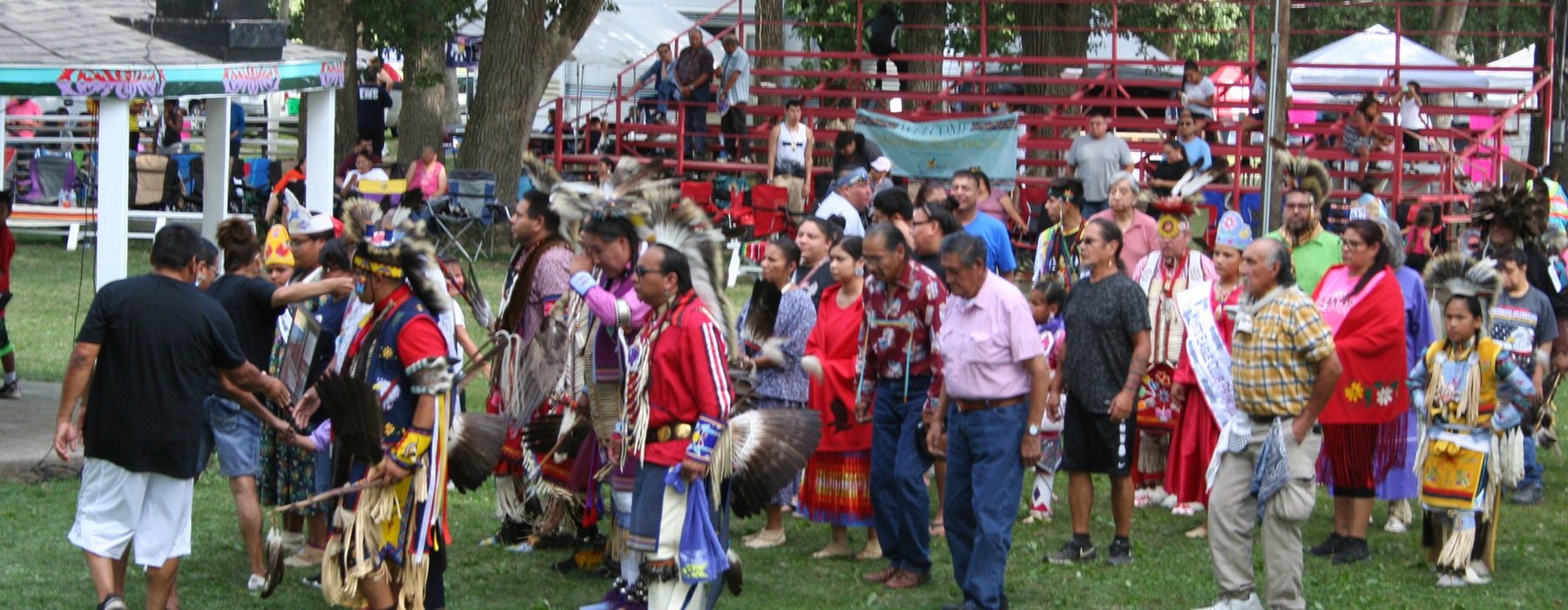 Men lining up to dance for a pow wow. Some in traditional clothes and some in modern clothes.