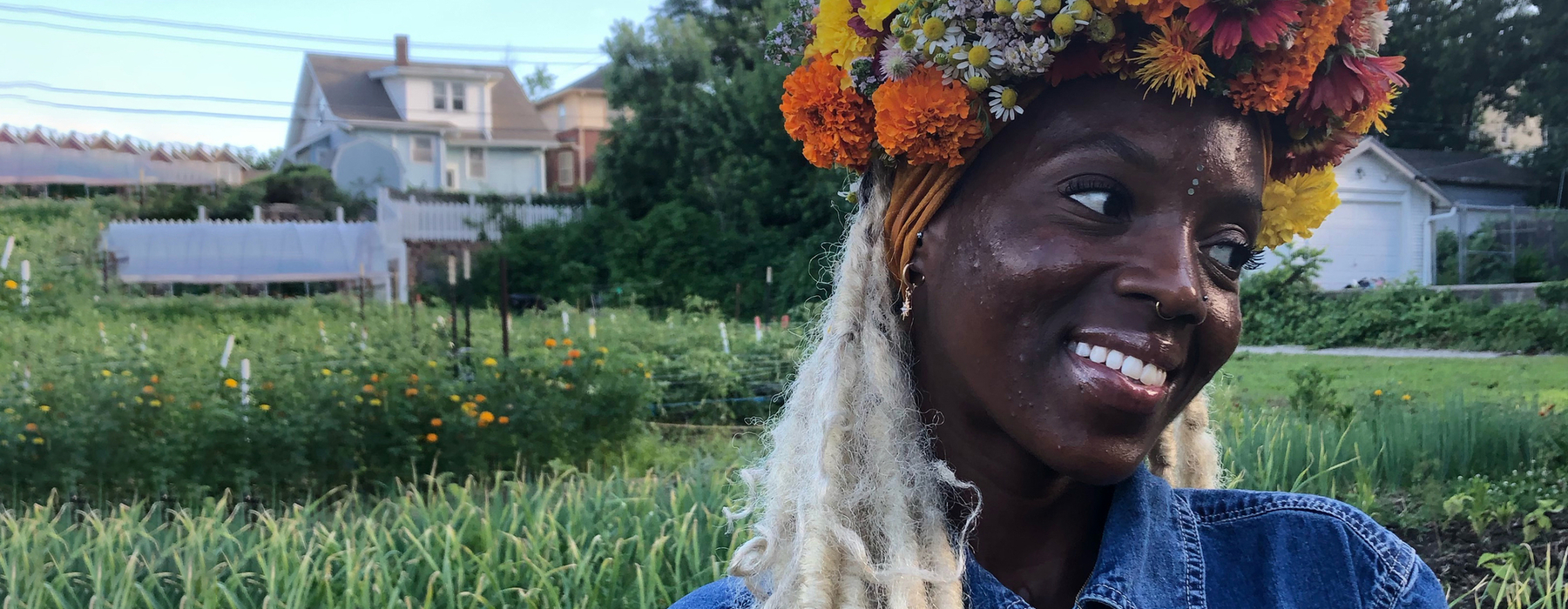 Woman stands in small urban flower field with a flower crown on her head