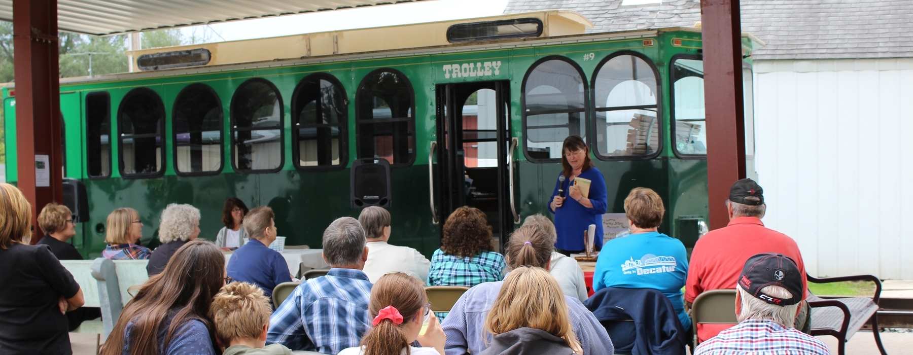 Woman author presenting in front of community art space trolly