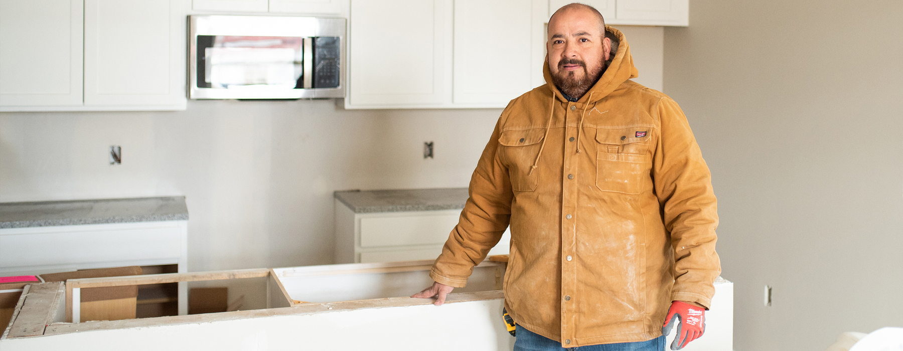 Man stands in front of an unfinished countertop in a kitchen