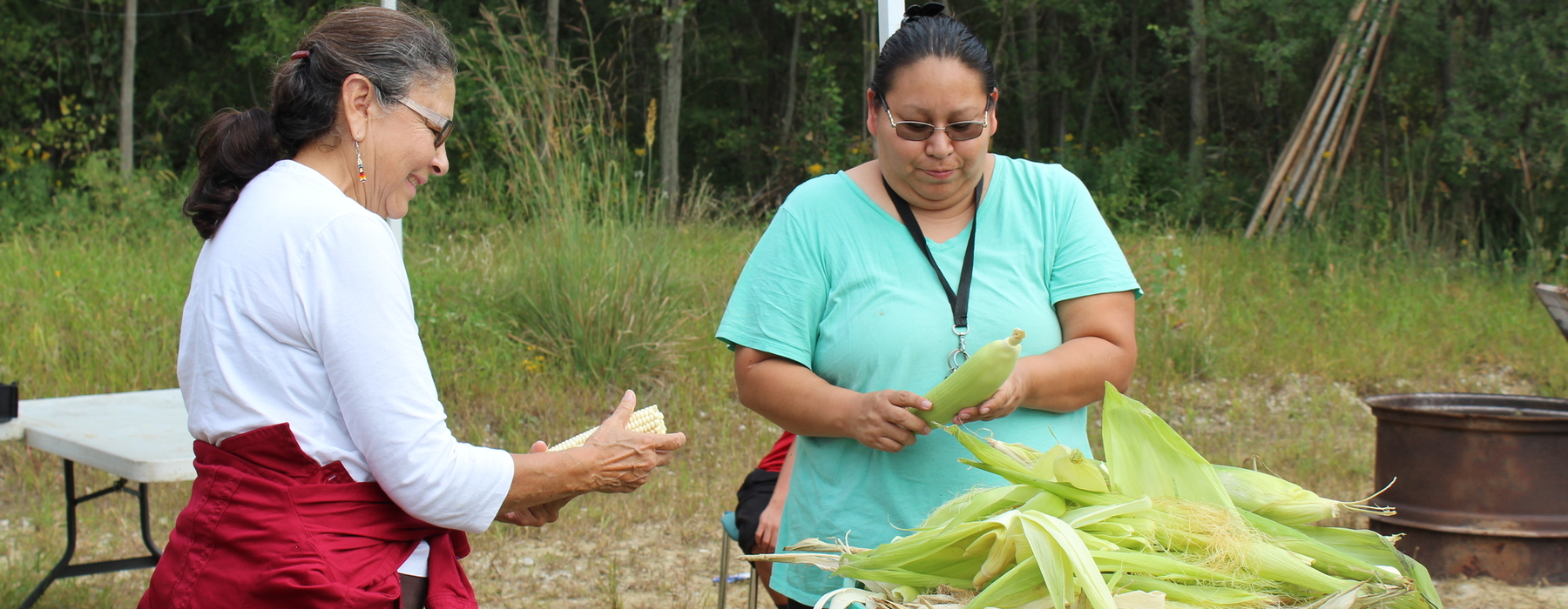 Two women husking corn